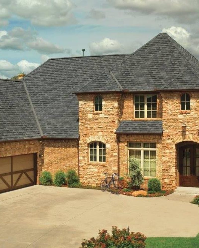 brown brick home with black roof