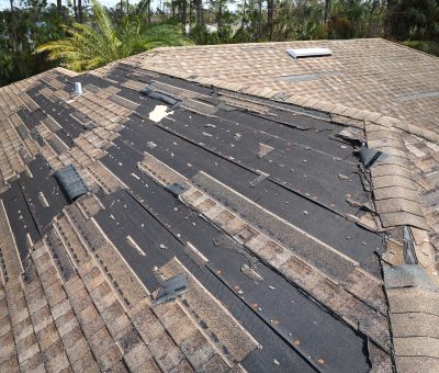 Wind damaged house roof with missing asphalt shingles after hurricane Ian in Florida. Repair of home rooftop concept.